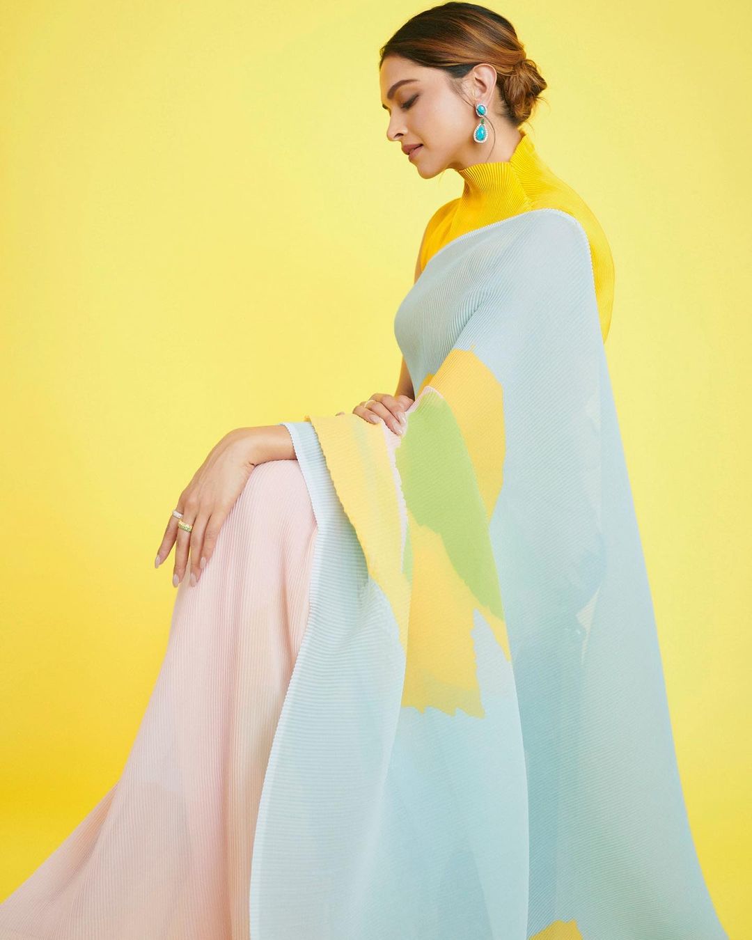  Deepika is 'Sunshine, Hope &amp; Happiness', as her caption says, in this spring-themed light blue and pink half-half pleated saree. The yellow background is a perfect choice for the photoshoot. (Image: Instagram)