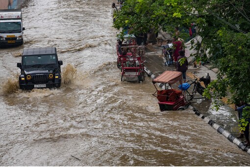 Delhi Flood News: Vehicle move through a flooded road near the Red Fort as the swollen Yamuna river floods low-lying areas on Thursday, July 13, 2023. (PTI Photo)