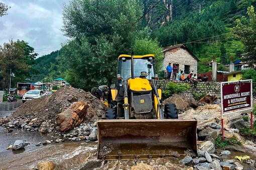  An earthmover removes debris and boulders washed along the floodwaters, in Manali on Friday (PTI Photo)