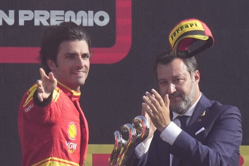 Ferrari driver Carlos Sainz of Spain, left, throws his hat as he celebrates on the podium his third place at the Formula One Italian Grand Prix auto race, at the Monza racetrack, in Monza, Italy, Sunday, Sept. 3, 2023. (AP Photo/Luca Bruno)
