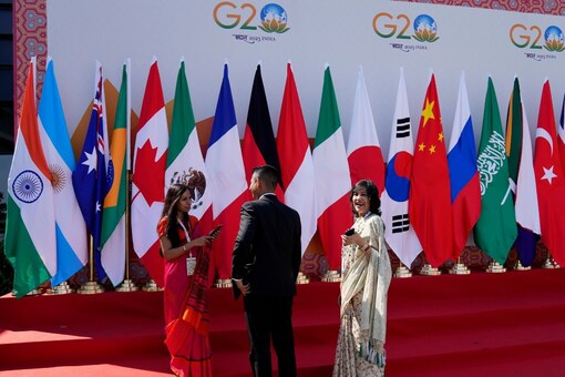 Delegates interact in front of flags of participating countries displayed at the venue of G-20 financial conclave in Bengaluru. (Credits: PTI)
