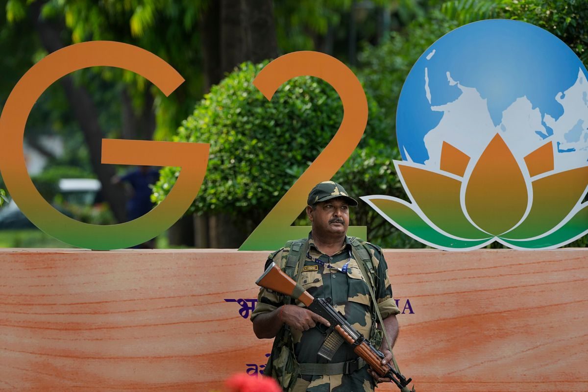 A security official stands guard near a G20 Summit logo installed at Shangri-La Hotel as part of preparations for the upcoming summit, in New Delhi