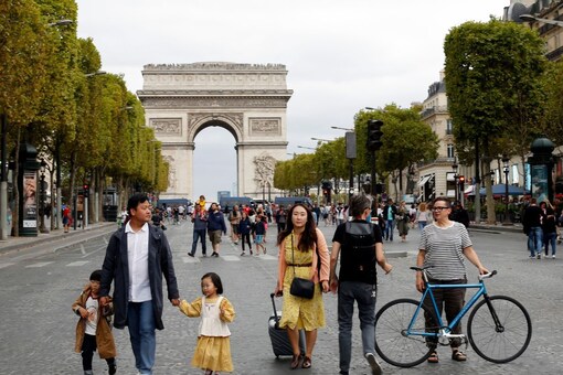 People walk on the champs Elysees avenue with the Arc de Triomphe in background, in Paris. (AP) 