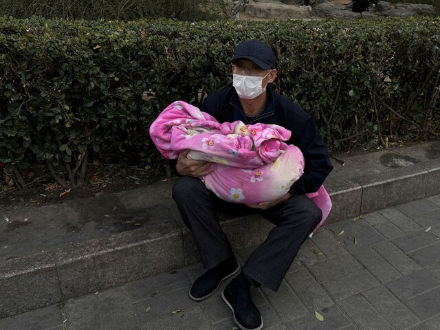 A man holding a child sits outside a children's hospital in Beijing, China. (Image: Reuters)