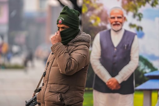 A policeman stands guard near a cutout portrait of Prime Minister Narendra Modi at the main market in Srinagar on Monday. (AP) 