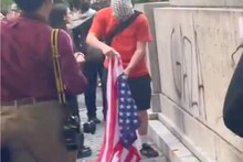 Anti-Israel protester prepares to set ablaze an American flag in Central Park. The man pictured here was part of a 1000-strong mob that wanted to disrupt the Met Gala. (Image: Mike Netter/X)