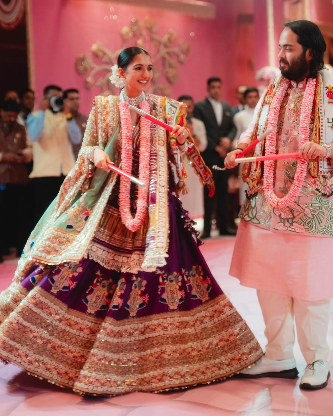 Anant and Radhika wore pink garlands and engaged in dandiya during the garba night, to celebrate their ensuing wedding. (Photo: Instagram/@rheakapoor) Anant and Radhika wore pink garlands and engaged in dandiya during the garba night, to celebrate their ensuing wedding. (Photo: Instagram/@rheakapoor)