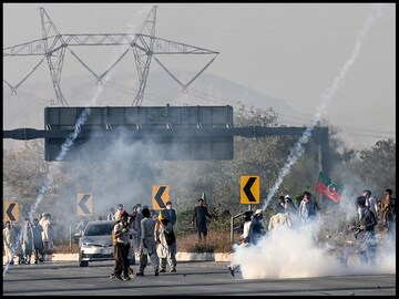 Imran Khan's supporters throw back teargas shells fired by riot policemen during their protest march to Islamabad. (AFP)