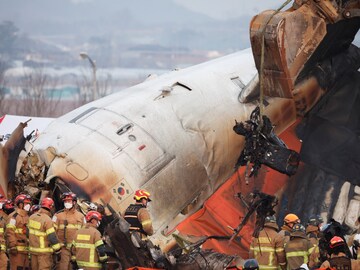 An excavator is used to lift burnt chairs from the wreckage of an aircraft that crashed after it went off the runway at Muan  Airport. (Reuters)