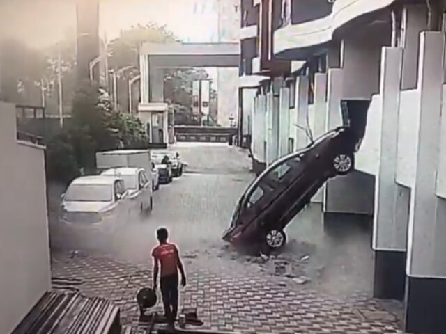 The car is seen resting with its rear end on the ground, leaning against the building after the fall. (Screengrab via X)