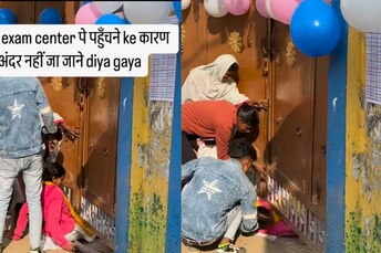 The girl slides through the gap between the gate and the ground, eventually squeezing her way inside. (News18 Hindi)