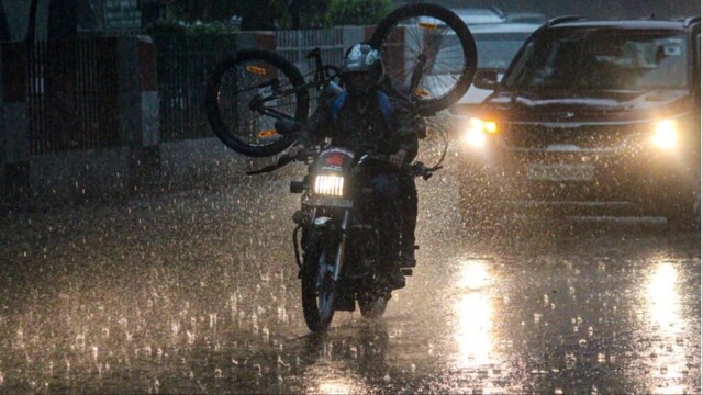 Meerut: Commuters transport a bicycle on a motorcycle amid rainfall on April 10 (Photo: PTI)