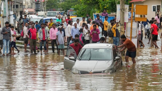 People attempt to push out a car from a waterlogged road after heavy rains, at Sai layout in Bengaluru, Monday, May 19, 2025. (PTI Photo)