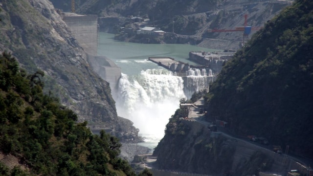 Water flows on the banks of Chenab River with the Baglihar hydroelectric project in the background, about 155 km (96 miles) northwest of Jammu, the winter capital of the troubled northern state of Jammu and Kashmir, October 2, 2005. World Bank-appointed observer Raymond Lefitte, who is visiting the site on Sunday, voiced optimism that the row over the Baglihar hydroelectric project, a project Islamabad opposes, will be sorted out, media reports said. Pakistan has raised objections over the height of the dam and said it violates the Indus Water Treaty. India says there is no substance in Pakistan's objections. REUTERS/Amit Gupta