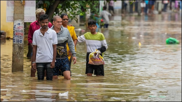 People wade through a waterlogged area after heavy rains in Bengaluru. (PTI file photo)