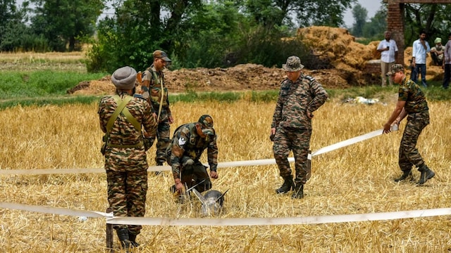 Security personnel survey the metal debris found at an open field at Makhan Windi village, in Amritsar district of Punjab on Thursday. (PTI)