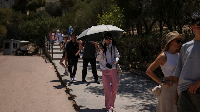 A tourist holds an umbrella to protect from the sun at the Acropolis hill archaeological site, as a heatwave hits Athens, Greece (Reuters image)