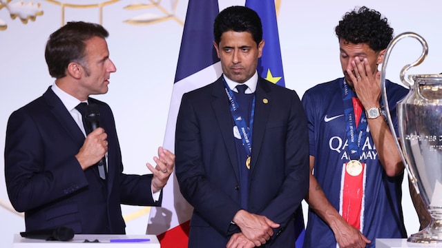 French President Emmanuel Macron, left, speaks as PSG captain Marquinhos, right, cries, and PSG president Nasser Al-Khelaifi listens after the team won the Champions League final (AP)