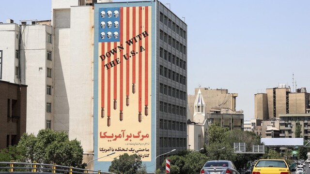 Commuters drive along a bridge near a building bearing a landmark anti-US mural in Tehran, on June 22, 2025. (AFP photo)
