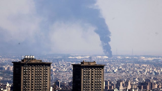 Smoke billows in the distance from an oil refinery following an Israeli strike on the Iranian capital Tehran on June 17, 2025. Israel and Iran exchanged fire again, the fifth day of strikes in their most intense confrontation in history, fuelling fears of a drawn-out conflict that could engulf the Middle East. (Photo by ATTA KENARE / AFP)
