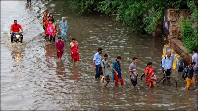 People wading through a waterlogged road in Gurugram after heavy rains. (PTI Image)