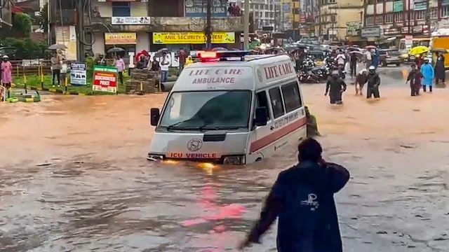 People push an ambulance while wading through a waterlogged road amid rainfall, in Mangaluru, Karnataka.