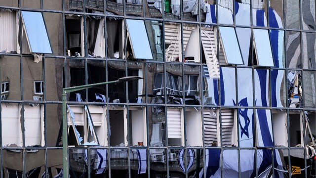 The Israeli flag is reflected in the windows of a damaged building in Ramat Gan, Israel, which was hit by a missile launched from Iran. (AP) 