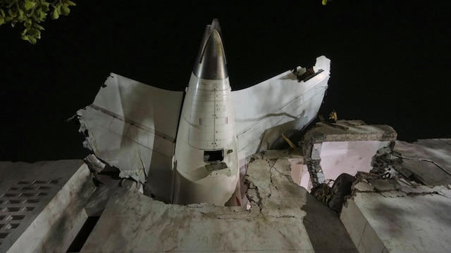 The tail of the airplane is seen stuck in a building at the site of an airplane that crashed in Ahmedabad. (PTI)