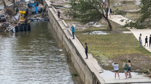 Onlookers walk along the banks of the Guadalupe River in Louise Hays Park, Saturday, July 5, 2025, in Kerrville, Texas. (AP Photo)
