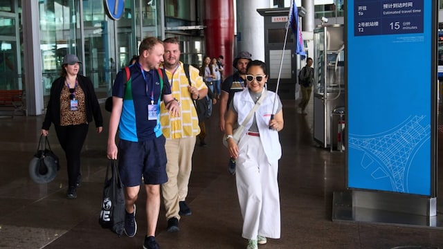  A tour guide leads tourists to the shutter bus at the Beijing Capital  Airport. (AP)