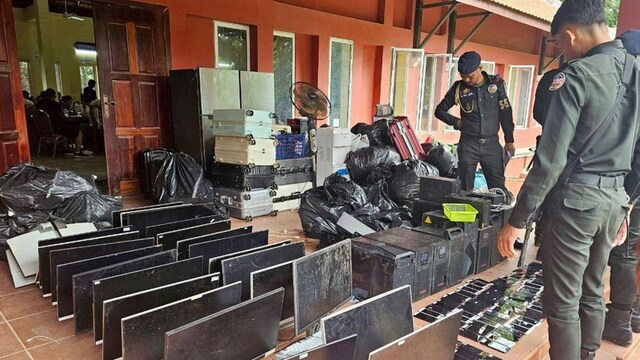 Cambodian military police personnel guard a cache of computers, smartphones and other equipment seized during a raid on a scam center in Kandal province on July 17, 2025. (AFP/Pool)