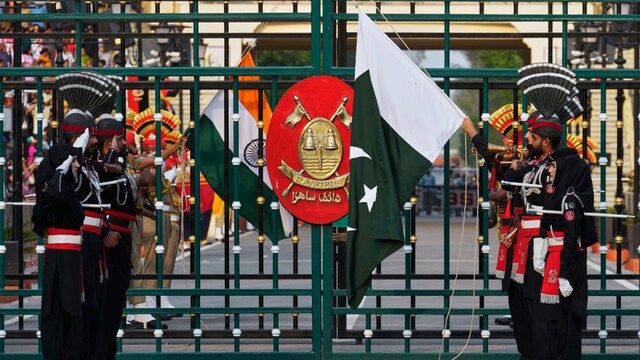 Pakistan's Rangers soldiers, in black, and Indian Border Security Forces soldiers, lower their flags during a daily closing ceremony at the Wagah (PTI)