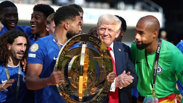 Chelsea's Reece James holds the championship trophy as he celebrates with teammates and President Donald Trump, second right, after Chelsea won against Paris St Germain in the Club World Cup final at MetLife Stadium in East Rutherford, N.J., Sunday, July 13, 2025. (Kevin Lamarque/Pool Photo via AP)
