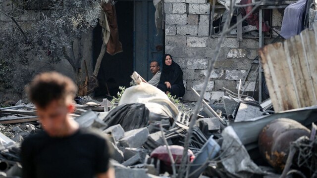 Palestinians sit amid the rubble of a house in the aftermath of an overnight Israeli strike that hit Nuseirat in the central Gaza Strip on July 13, 2025 (AFP)