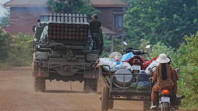 Cambodians drive behind a military vehicle (AP)