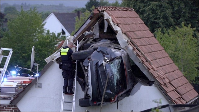 A police officer checks a car stuck in the wall of a barn following an accident in Germany. (AP)