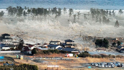Waves from a tsunami hit residences after a powerful earthquake in Natori, Miyagi prefecture, Japan, on March 11, 2011. (Kyodo News via AP, File)