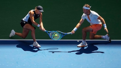 Casper Ruud, of Norway, left, plays a shot as partner Iga Swiatek, left, of Poland, covers during their mixed doubles match at the U.S. Open tennis championships, Tuesday, Aug. 19, 2025, in New York. (AP Photo/Yuki Iwamura)
