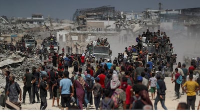 Palestinians climb onto trucks as they seek for aid supplies that entered Gaza through Israel in Beit Lahia, northern Gaza Strip, August 1, 2025. REUTERS