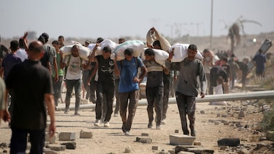 Palestinians return with bags from a food distribution point run by the US and Israeli-backed Gaza Humanitarian Foundation (GHF) group in the central Gaza Strip on August 3. (AFP photo)