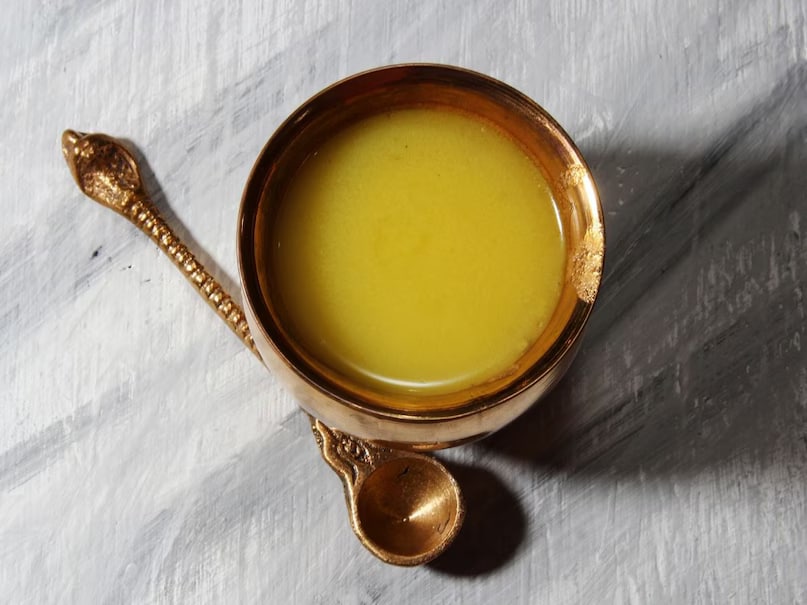 Ayurveda recommends taking one spoonful (5-10 grams) of desi ghee on an empty stomach after waking up. It can be consumed plain or mixed with lukewarm water. However, individuals with diabetes, high cholesterol, or obesity should consult a doctor before adding it to their diet. (News18 Hindi)