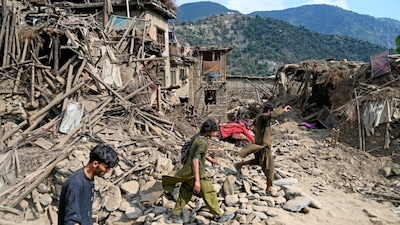 Afghans walk past damaged houses, after earthquakes at Mazar Dara village in Nurgal district, Kunar province, in Eastern Afghanistan. (AFP photo)