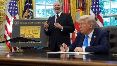 US Secretary of Commerce Howard Lutnick speaks while standing next to US President Donald Trump, as a 