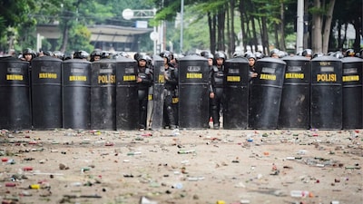Debris litter the street as police officers take their position following violent protests against lawmakers' perks and police brutality after a delivery rider was allegedly run over by a police vehicle during clashes with student protesters, in Jakarta, Indonesia, on August 30. (AP Photo)