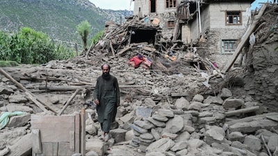 An man Afghan walks past a damaged house following earthquakes in the Mazar Dara village of Nurgal, a district of the Kunar Province, in Eastern Afghanistan (AFP)