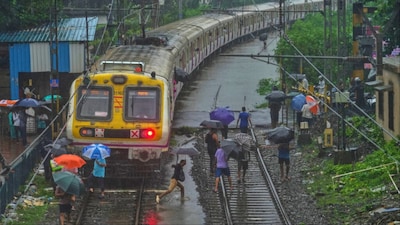 Commuters walk on waterlogged railway tracks after trains were disrupted due to heavy rainfall in Mumbai (File photo/PTI)