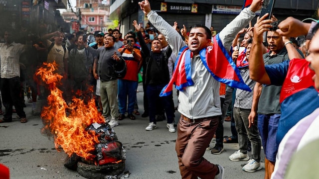 People displaying Nepal's national flag burn tyres during a demonstration to condemn the police's deadly crackdown on protesters in Kathmandu on September 9. (AFP)