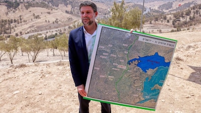 Israeli far-right finance minister Bezalel Smotrich holds a map of an area near the settlement of Maale Adumim, a land corridor known as E1, outside Jerusalem in the occupied West Bank. (Image: Menahem Kahana/AFP) 
