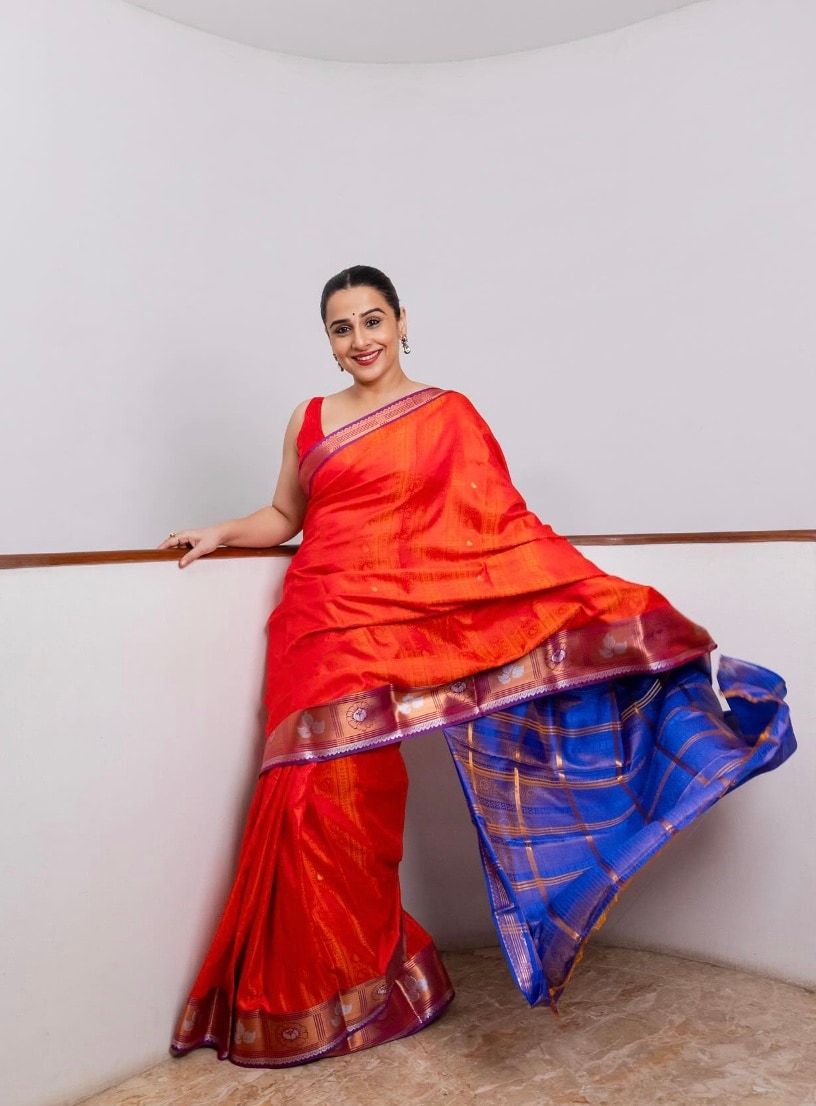 An orange silk saree with a blue border and a sleeveless blouse was Vidya's Navratri Day 7 look. An orange silk saree with a blue border and a sleeveless blouse was Vidya's Navratri Day 7 look.