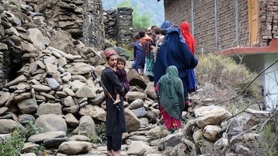 Local residents walk by a house destroyed by an earthquake that killed many people and destroyed villages in eastern Afghanistan, in Mazar Dara, Kunar province on Monday. (AP)
